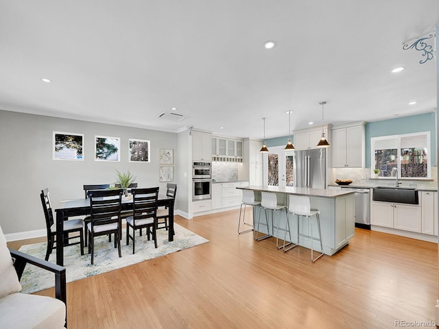 kitchen featuring appliances with stainless steel finishes, a center island, decorative light fixtures, tasteful backsplash, and sink