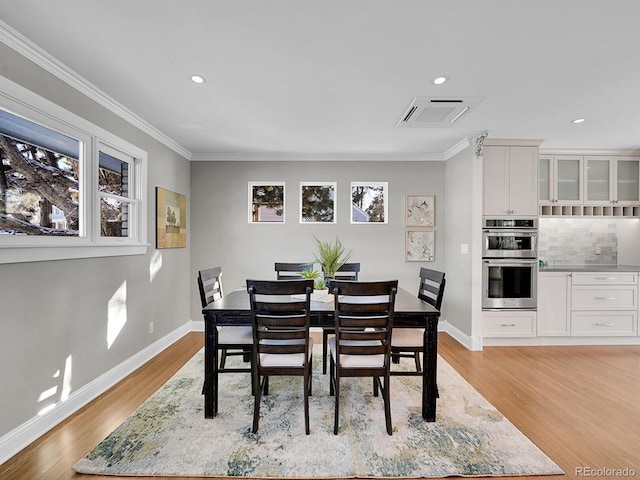 dining space with crown molding and light wood-type flooring