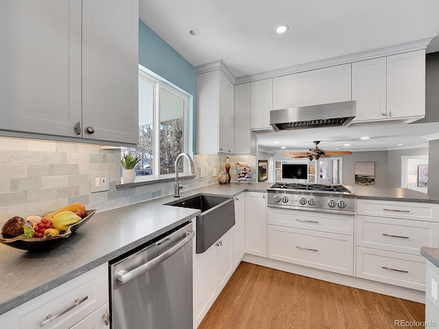 kitchen featuring light hardwood / wood-style floors, white cabinetry, sink, wall chimney range hood, and stainless steel appliances