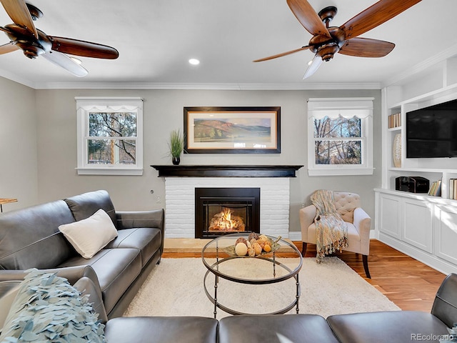 living room featuring a brick fireplace, light hardwood / wood-style flooring, and crown molding