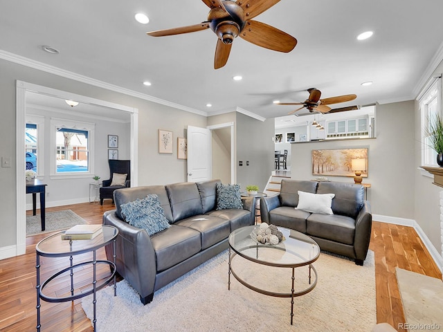 living room featuring light wood-type flooring, a wealth of natural light, and ornamental molding