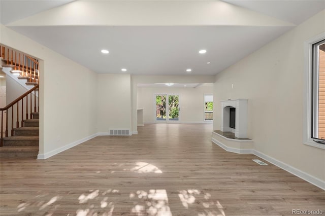 308 Oswego St, Aurora, CO 80010 - unfurnished living room featuring stairway, vaulted ceiling, light wood-type flooring, recessed lighting, and a fireplace with raised hearth
