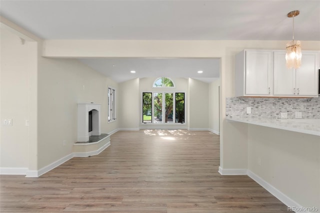 308 Oswego St, Aurora, CO 80010 - unfurnished living room with lofted ceiling, light wood-style flooring, recessed lighting, baseboards, and a fireplace with raised hearth