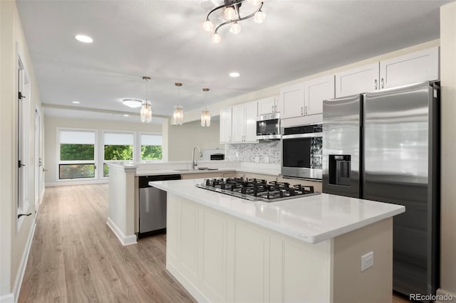 308 Oswego St, Aurora, CO 80010 - kitchen featuring stainless steel appliances, a sink, a peninsula, light wood finished floors, and light countertops