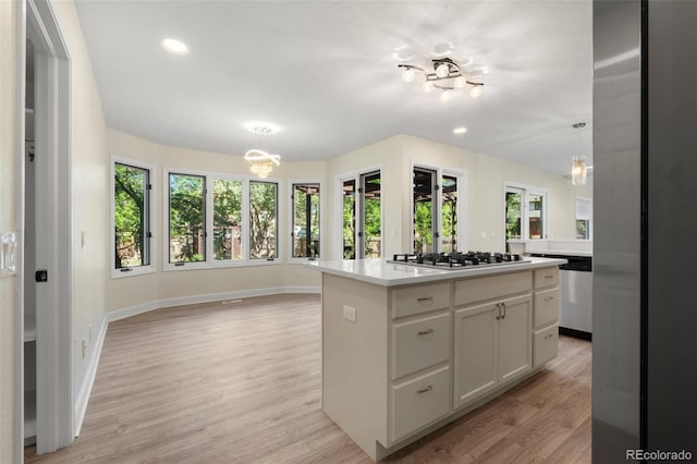 308 Oswego St, Aurora, CO 80010 - kitchen with stainless steel appliances, a center island, white cabinets, light wood-style floors, and light countertops