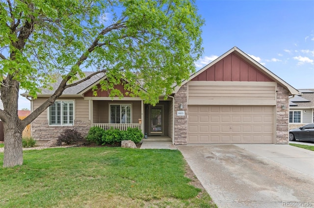 view of front of house with covered porch, an attached garage, concrete driveway, a front lawn, and stone siding