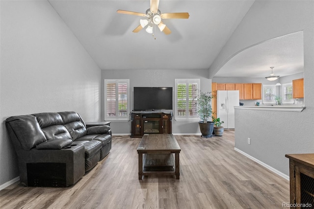 living room with vaulted ceiling, ceiling fan, light wood-style floors, and baseboards