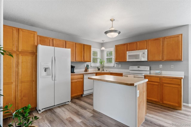 kitchen with white appliances, a sink, light wood-style flooring, light countertops, and a textured ceiling