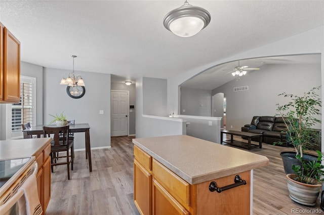 kitchen with a ceiling fan, a center island, light wood-type flooring, pendant lighting, and light countertops
