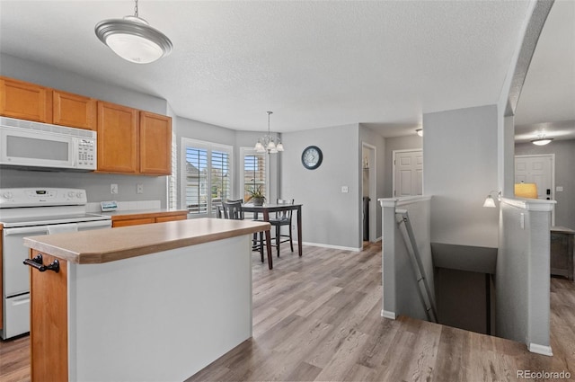 kitchen with white appliances, light wood-type flooring, a textured ceiling, light countertops, and a chandelier