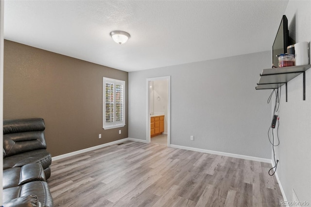 living area with light wood-style floors, baseboards, and a textured ceiling