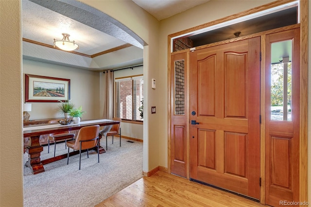 2613 Fox Run Ct, Fort Collins, CO 80526 - entrance foyer featuring light wood-type flooring, baseboards, arched walkways, a tray ceiling, and ornamental molding