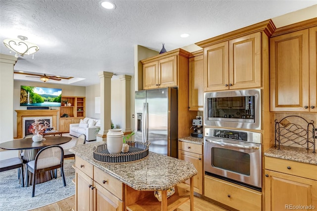 2613 Fox Run Ct, Fort Collins, CO 80526 - kitchen with appliances with stainless steel finishes, ceiling fan, light wood finished floors, a textured ceiling, and decorative columns