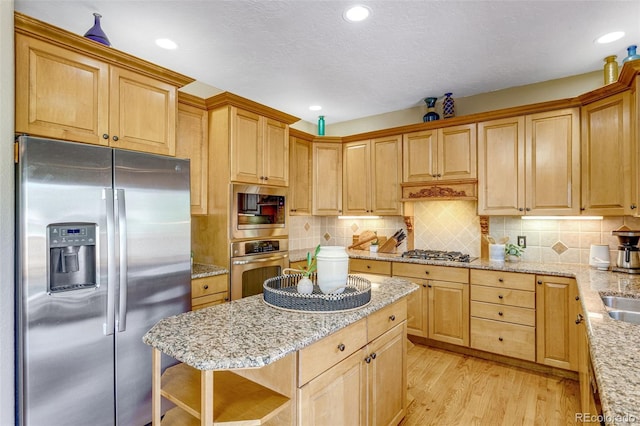 2613 Fox Run Ct, Fort Collins, CO 80526 - kitchen with stainless steel appliances, light wood-style floors, light stone counters, a center island, and decorative backsplash