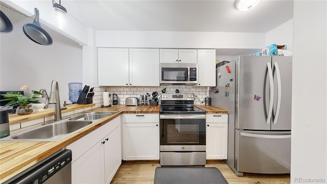 kitchen featuring stainless steel appliances, sink, white cabinets, and wood counters