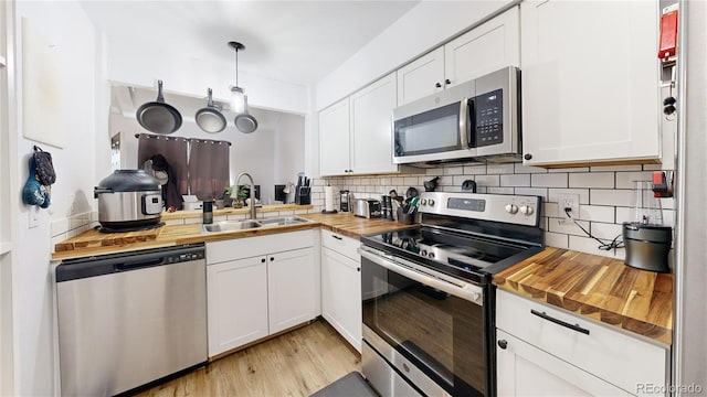 kitchen featuring white cabinetry, stainless steel appliances, and butcher block countertops