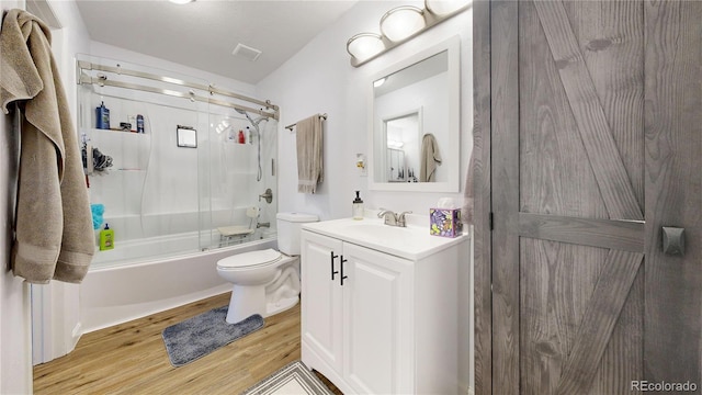 full bathroom featuring toilet, wood-type flooring, shower / bath combination with glass door, and vanity