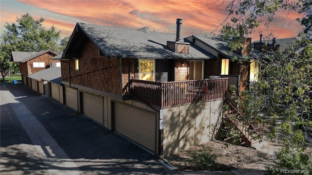 property exterior at dusk featuring a garage and a balcony