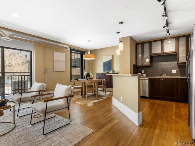 kitchen featuring tasteful backsplash, hanging light fixtures, stainless steel dishwasher, dark brown cabinets, and dark hardwood / wood-style flooring