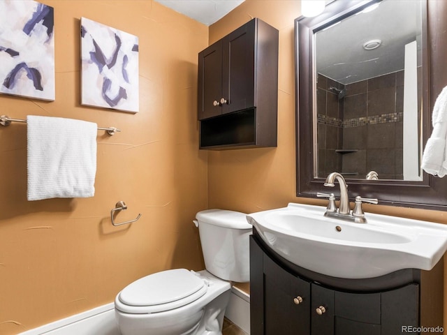 bathroom with toilet, vanity, and tiled shower