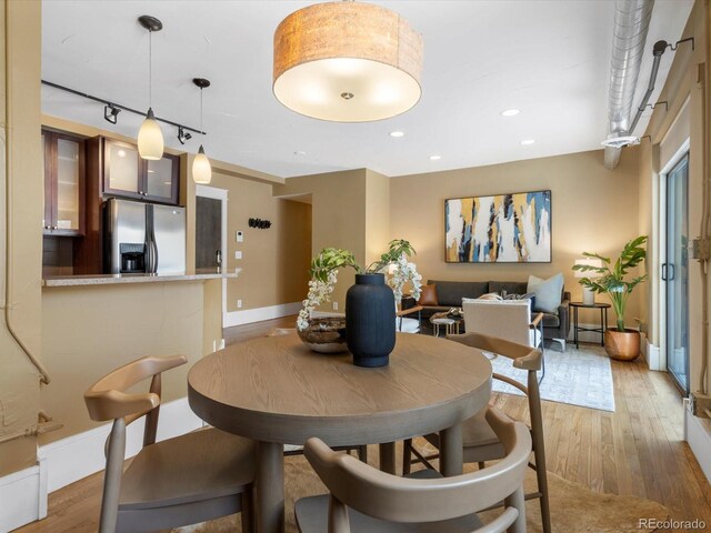 dining space with light wood-style flooring, rail lighting, recessed lighting, and baseboards