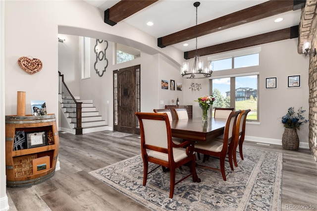 dining room featuring a chandelier, plenty of natural light, baseboards, beam ceiling, and wood finished floors