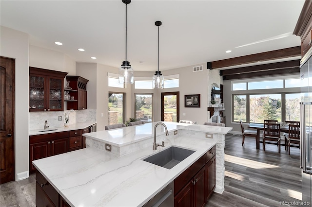 kitchen with a sink, dark wood-type flooring, glass insert cabinets, decorative light fixtures, and recessed lighting