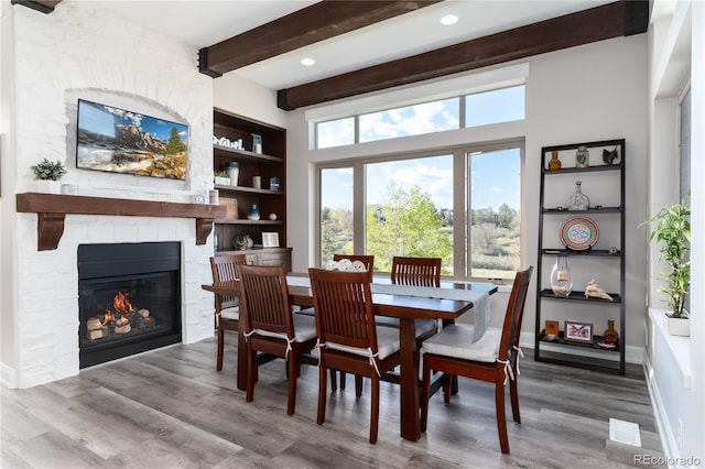 dining space with beam ceiling, wood finished floors, a fireplace, baseboards, and recessed lighting