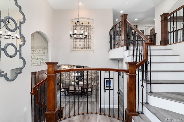stairway with a chandelier, wood finished floors, and recessed lighting