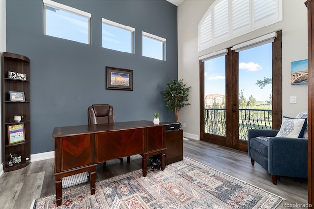 office area featuring a high ceiling, wood finished floors, baseboards, and french doors