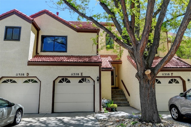 11358 W 85th Pl Unit E, Arvada, CO 80005 - view of front of property featuring a tiled roof, a garage, stucco siding, and driveway