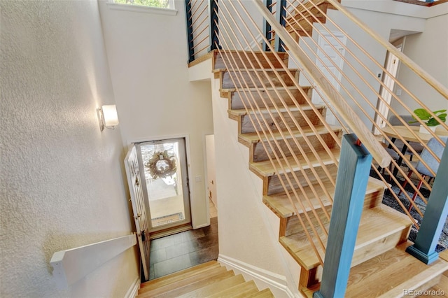 11358 W 85th Pl Unit E, Arvada, CO 80005 - stairs featuring wood finished floors, a textured wall, a high ceiling, and baseboards