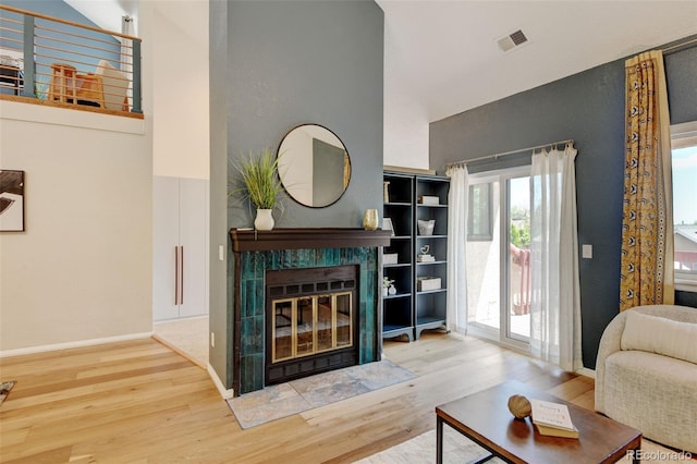 11358 W 85th Pl Unit E, Arvada, CO 80005 - living room with wood finished floors, a towering ceiling, a tiled fireplace, and baseboards