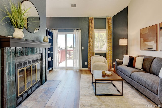 11358 W 85th Pl Unit E, Arvada, CO 80005 - living area featuring wood finished floors, a tile fireplace, an accent wall, and baseboards