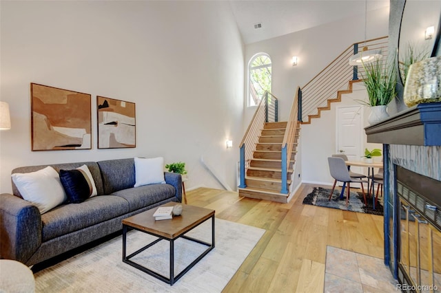 11358 W 85th Pl Unit E, Arvada, CO 80005 - living room with high vaulted ceiling, stairway, light wood finished floors, and a fireplace with flush hearth