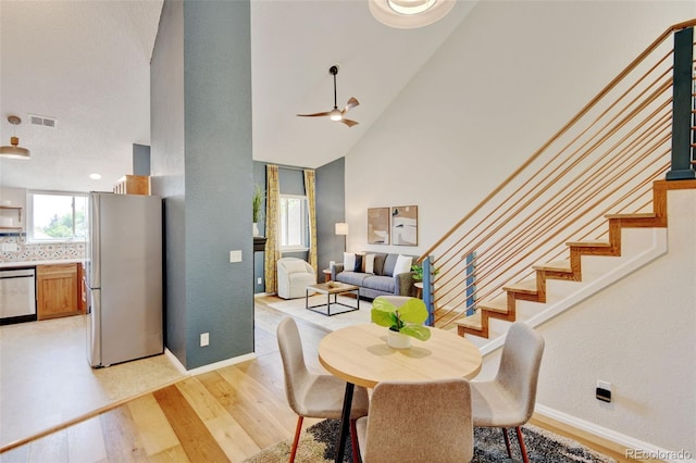 11358 W 85th Pl Unit E, Arvada, CO 80005 - dining area featuring light wood finished floors, stairway, a ceiling fan, high vaulted ceiling, and baseboards