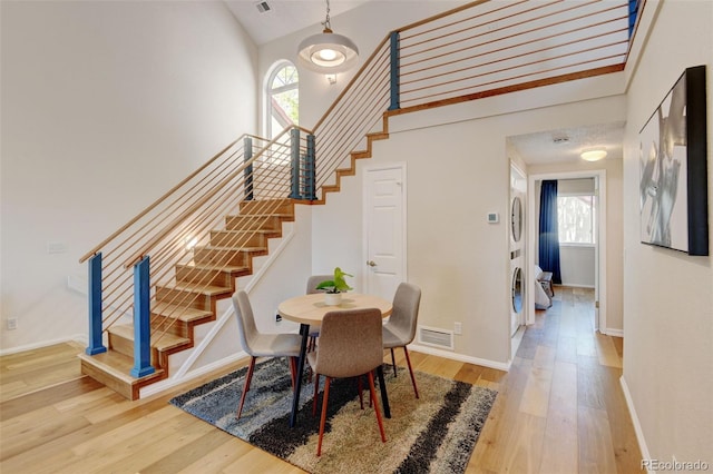 11358 W 85th Pl Unit E, Arvada, CO 80005 - dining space featuring wood finished floors, stairs, stacked washer / dryer, plenty of natural light, and high vaulted ceiling