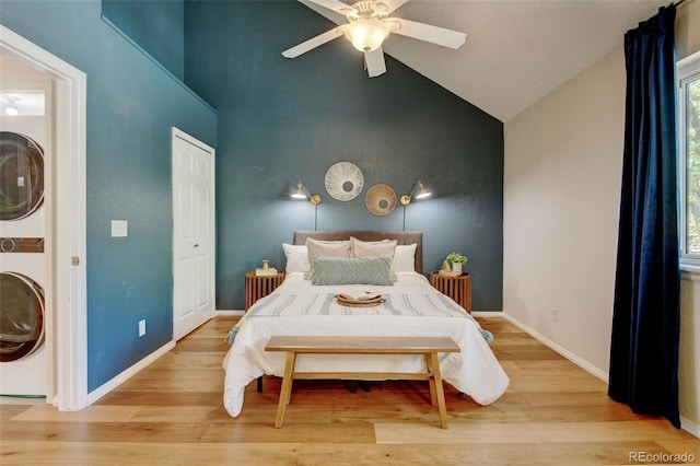 11358 W 85th Pl Unit E, Arvada, CO 80005 - bedroom featuring estacked washer and dryer, light wood-type flooring, baseboards, a ceiling fan, and high vaulted ceiling