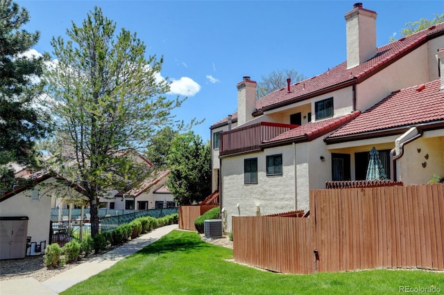 11358 W 85th Pl Unit E, Arvada, CO 80005 - back of house with stucco siding, a tile roof, central AC unit, a chimney, and a balcony