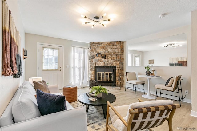 living room featuring a stone fireplace, a textured ceiling, and light wood-type flooring