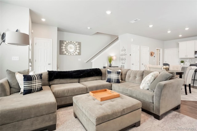 living room featuring light wood-style flooring, stairway, and recessed lighting