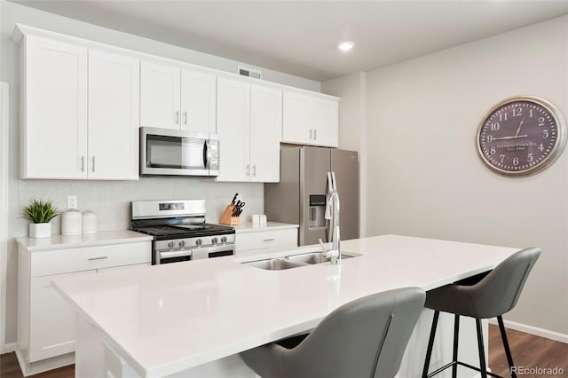 kitchen with stainless steel appliances, light countertops, and a kitchen island with sink