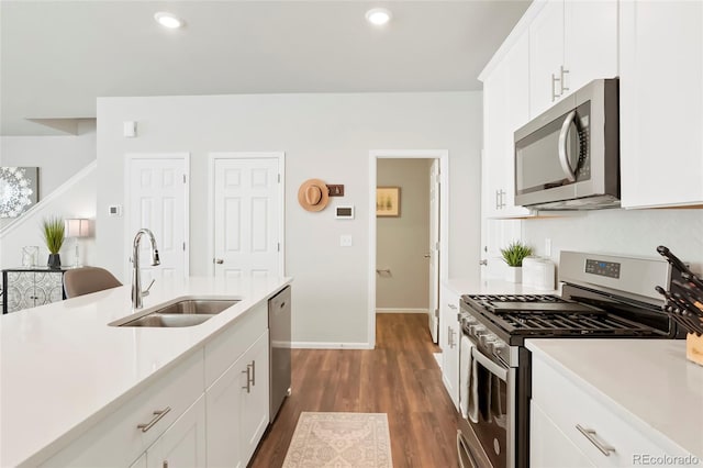 kitchen featuring white cabinets, dark wood finished floors, stainless steel appliances, light countertops, and a sink