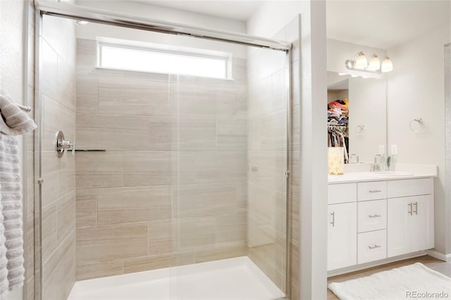 bathroom with a stall shower, a walk in closet, and vanity