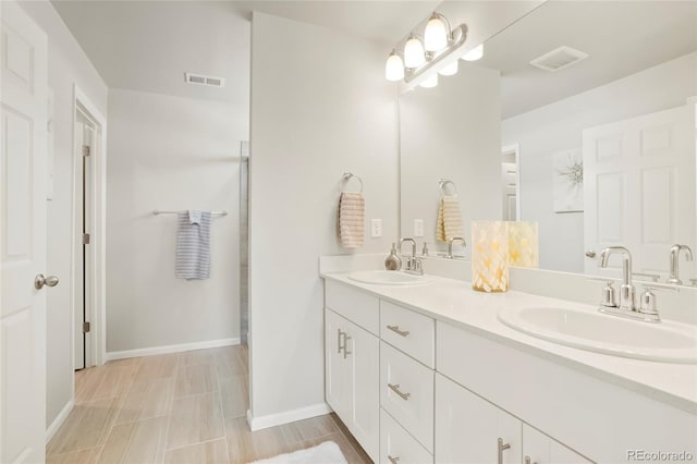 bathroom featuring double vanity, visible vents, baseboards, and a sink