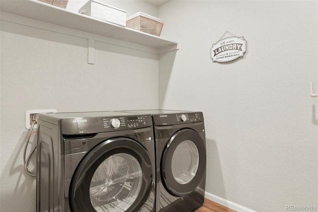 clothes washing area with laundry area, baseboards, separate washer and dryer, and wood finished floors