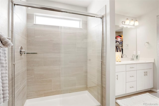 full bath with a stall shower, a spacious closet, and vanity
