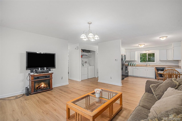 1641 Biscay Cir, Aurora, CO 80011 - living room featuring a chandelier, light wood finished floors, washer and clothes dryer, and a glass covered fireplace