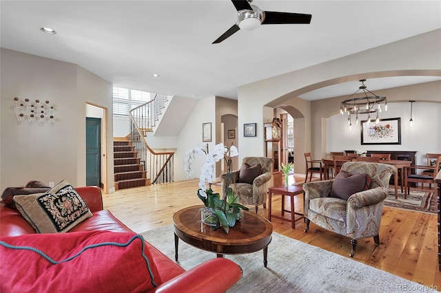 living room with stairway, recessed lighting, arched walkways, a ceiling fan, and wood-type flooring