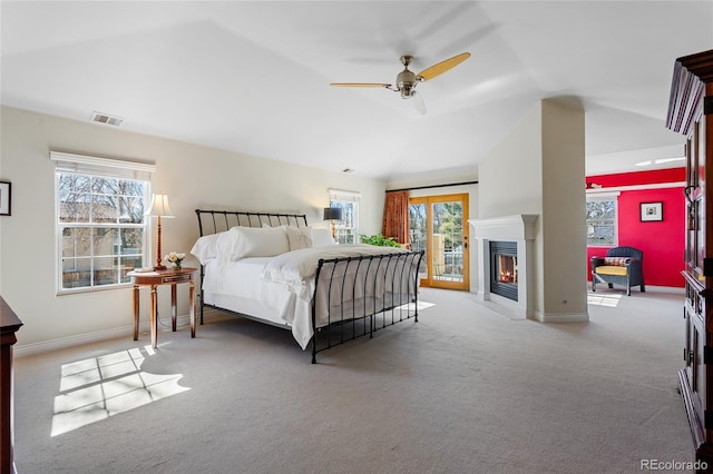 bedroom featuring visible vents, a fireplace with flush hearth, access to outside, baseboards, and vaulted ceiling